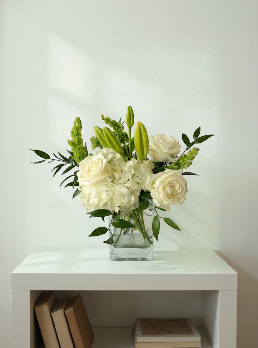 Lakewood Florist Ivory & Grace arrangement: white roses, lilies, hydrangeas, and greenery in a glass vase.