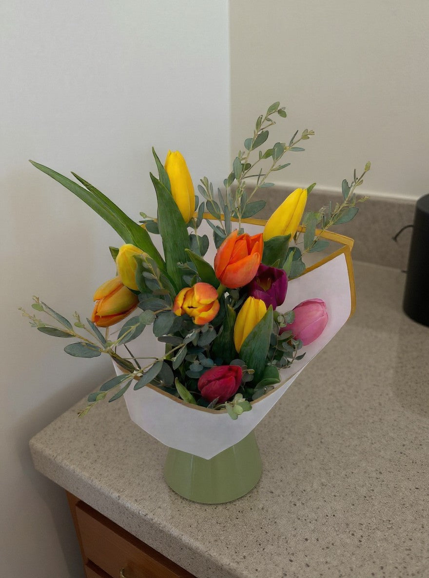 Lakewood Florist mixed tulip bouquet with yellow, orange, red, and pink tulips and greenery.