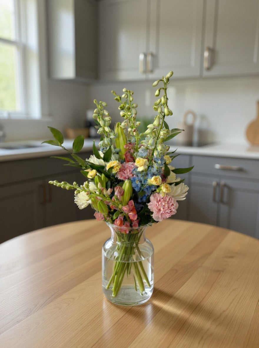 Lakewood Florist pastel spring bouquet with pink, white, lavender, and yellow flowers, wrapped in pink paper.