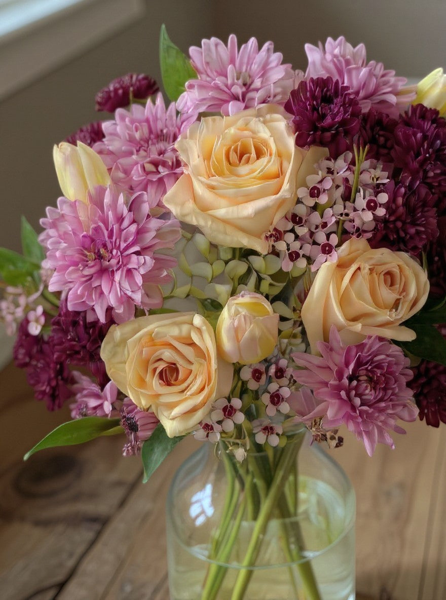 Lakewood Florist peach and purple floral bouquet with roses, chrysanthemums, and tulips in a glass vase.