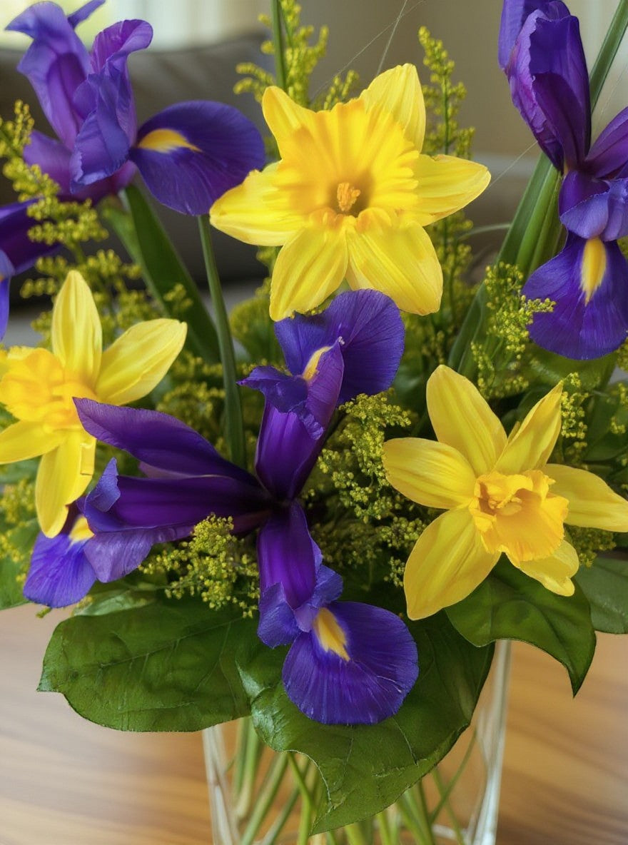 Lakewood Florist Violet Sunrise arrangement with yellow daffodils and purple irises in a clear vase.